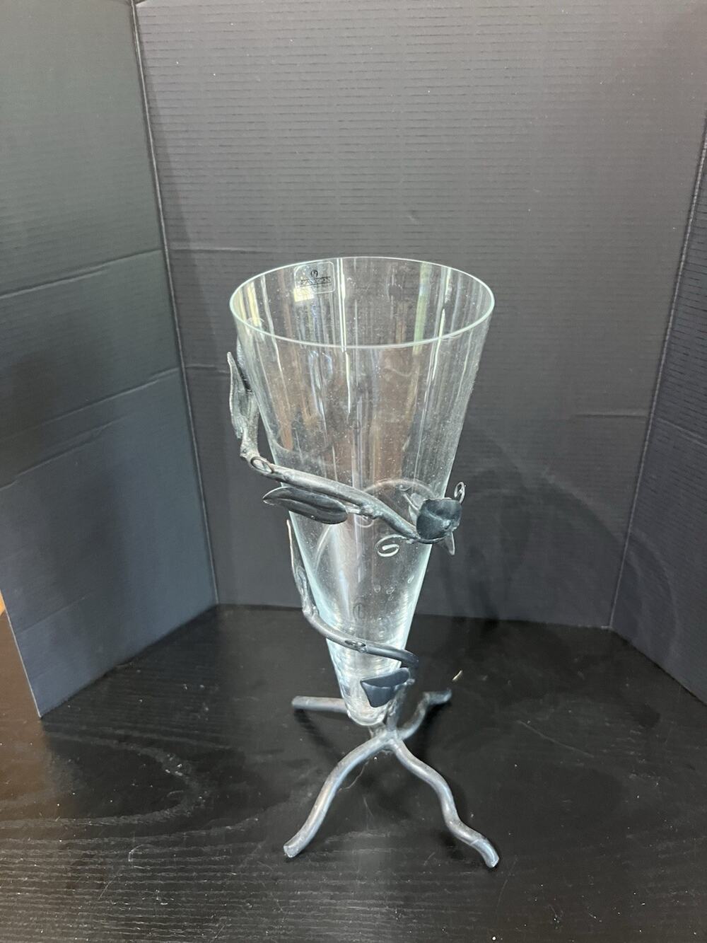 Wrought iron footed vase with vine leaf design,